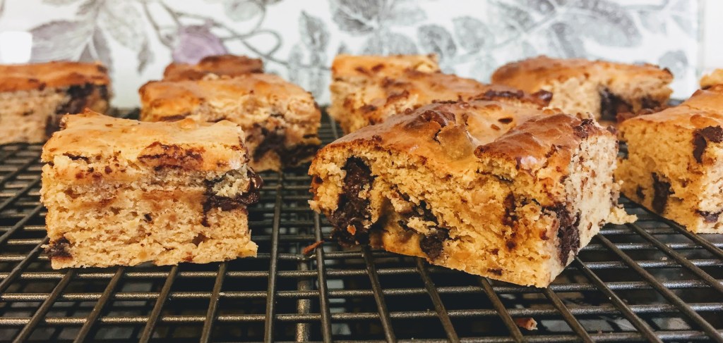 Fudgy, golden, vegan and gluten-free blondies, chopped into squares on a cooling rack.