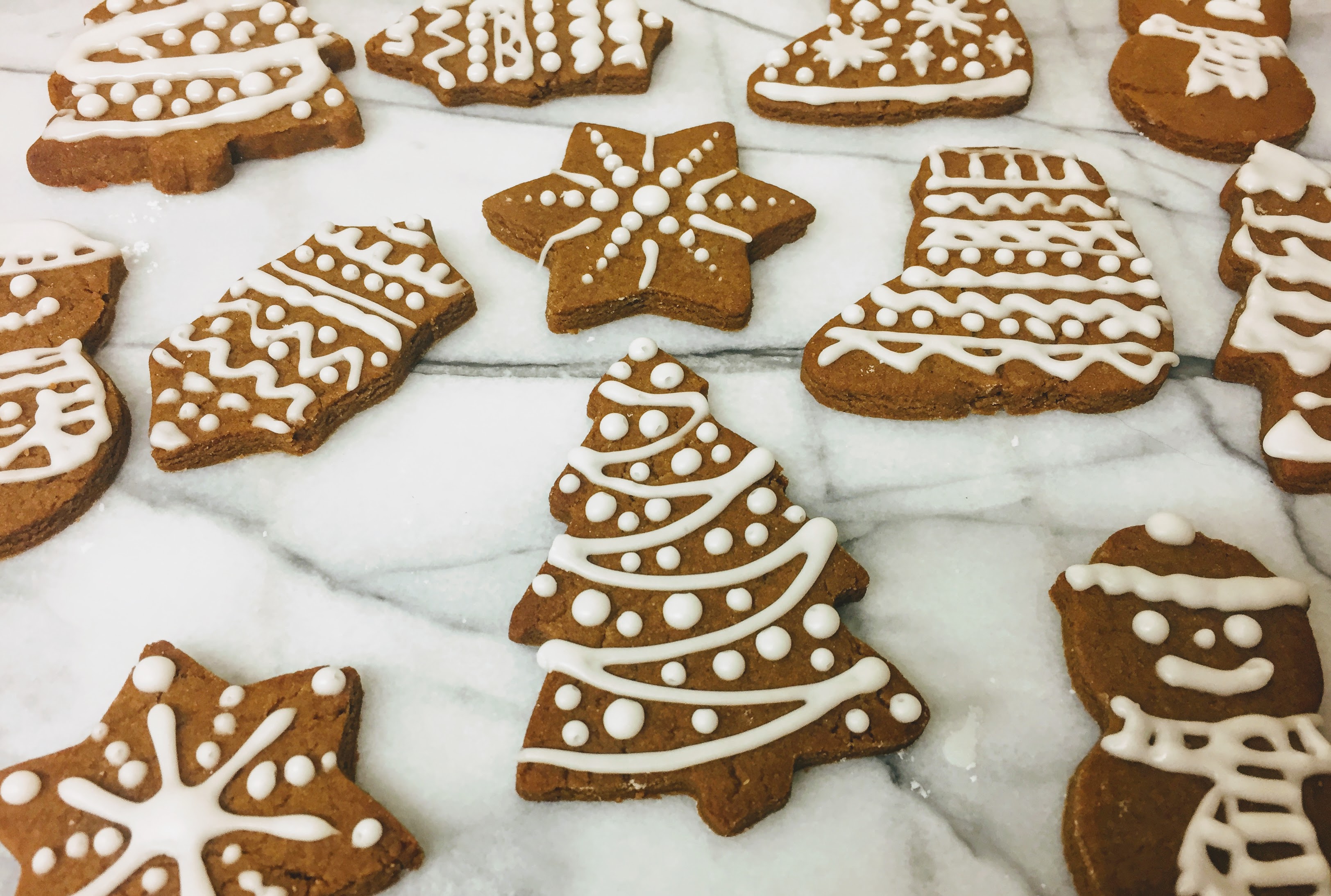A side view of the gingerbread biscuits, which are about half a centimeter thick. A christmas tree is at the front of the picture with icing piped like tinsel and baubles.