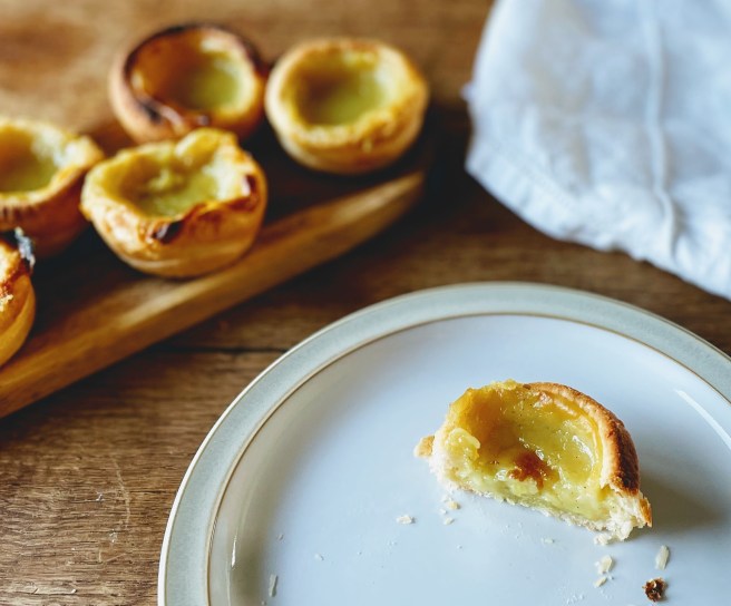 A pastel de nata sliced in half to reveal the smooth and silky set custard, surrounded by flaky puff pastry.  