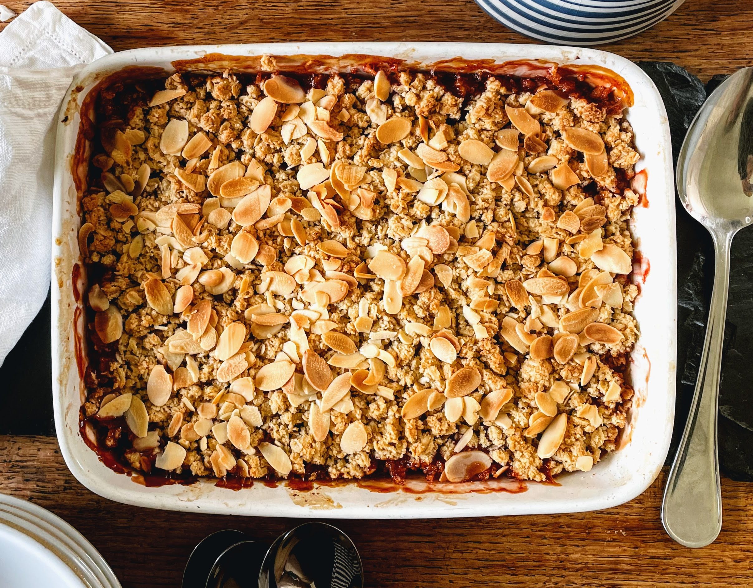 Rhubarb, orange and almond crumble, straight from the over. There's a crumbly, oaty topping scattered with golden brown flaked almonds, and patches of deeply caramelized fruit juice that has bubbled up the side.