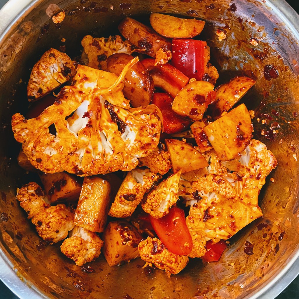 The raw cauliflower and potatoes coated in the marinade before roasting.